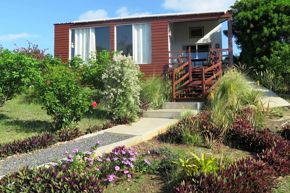 A two-story building with a wooden exterior, a front porch, and a staircase leading to the entrance.