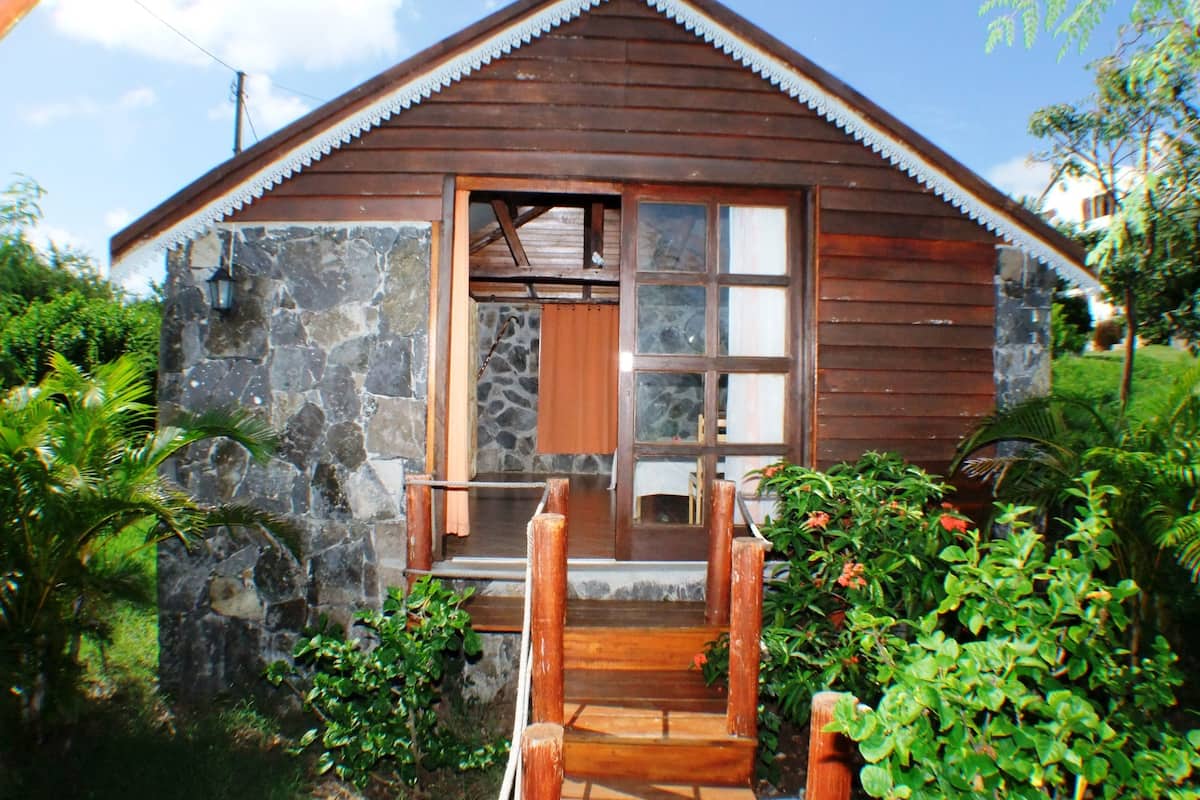 A wooden cabin with a stone facade, a wooden porch, and a stone wall.