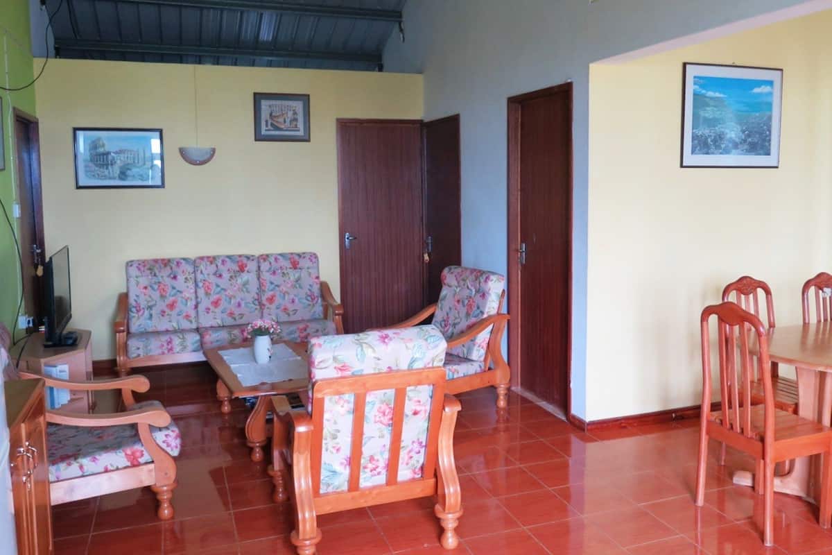 A living room with a sofa, chairs, a television, and a dining table.