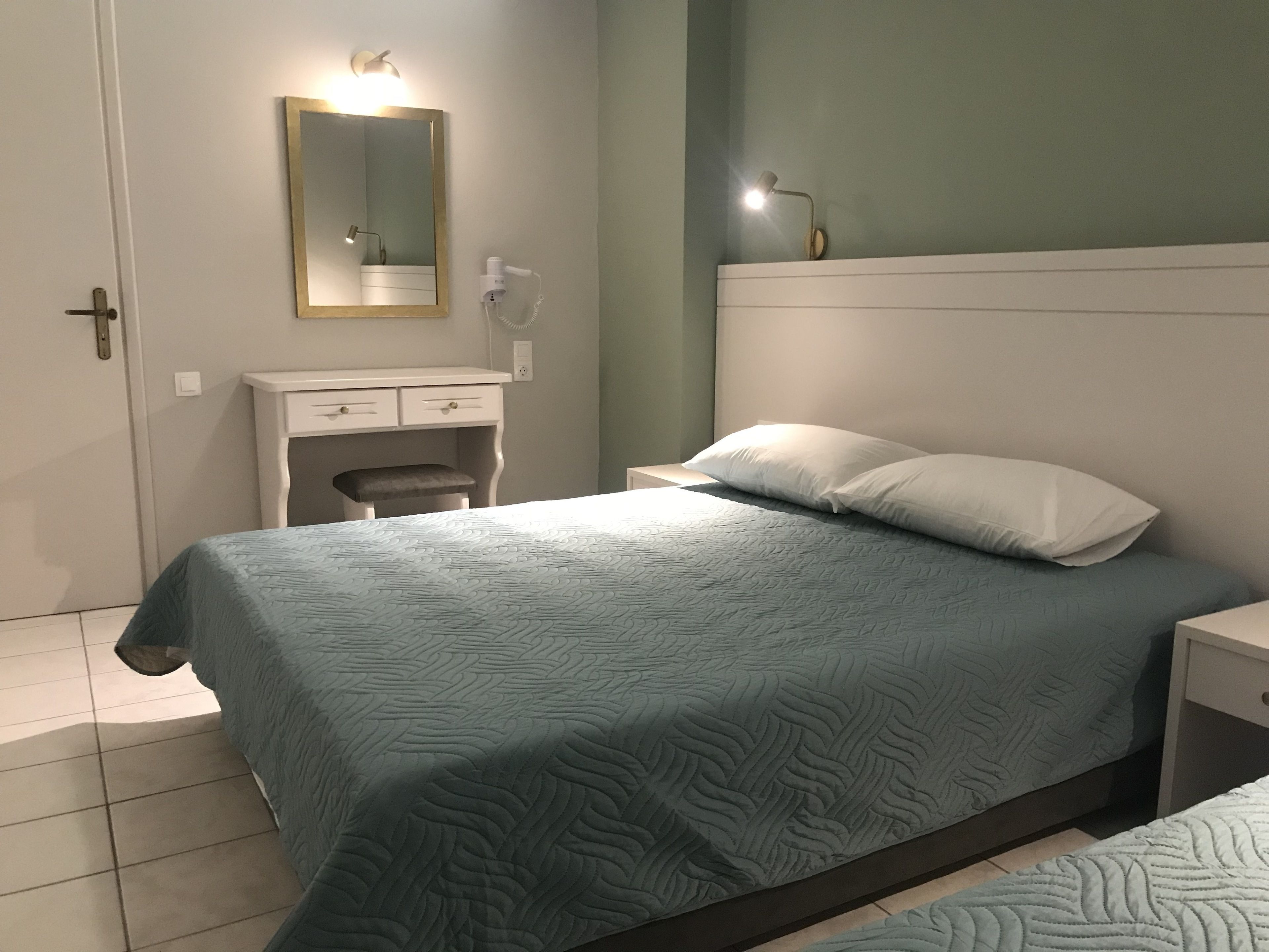 A bedroom with a bed, bedside table, nightstand, dresser, and a mirror.