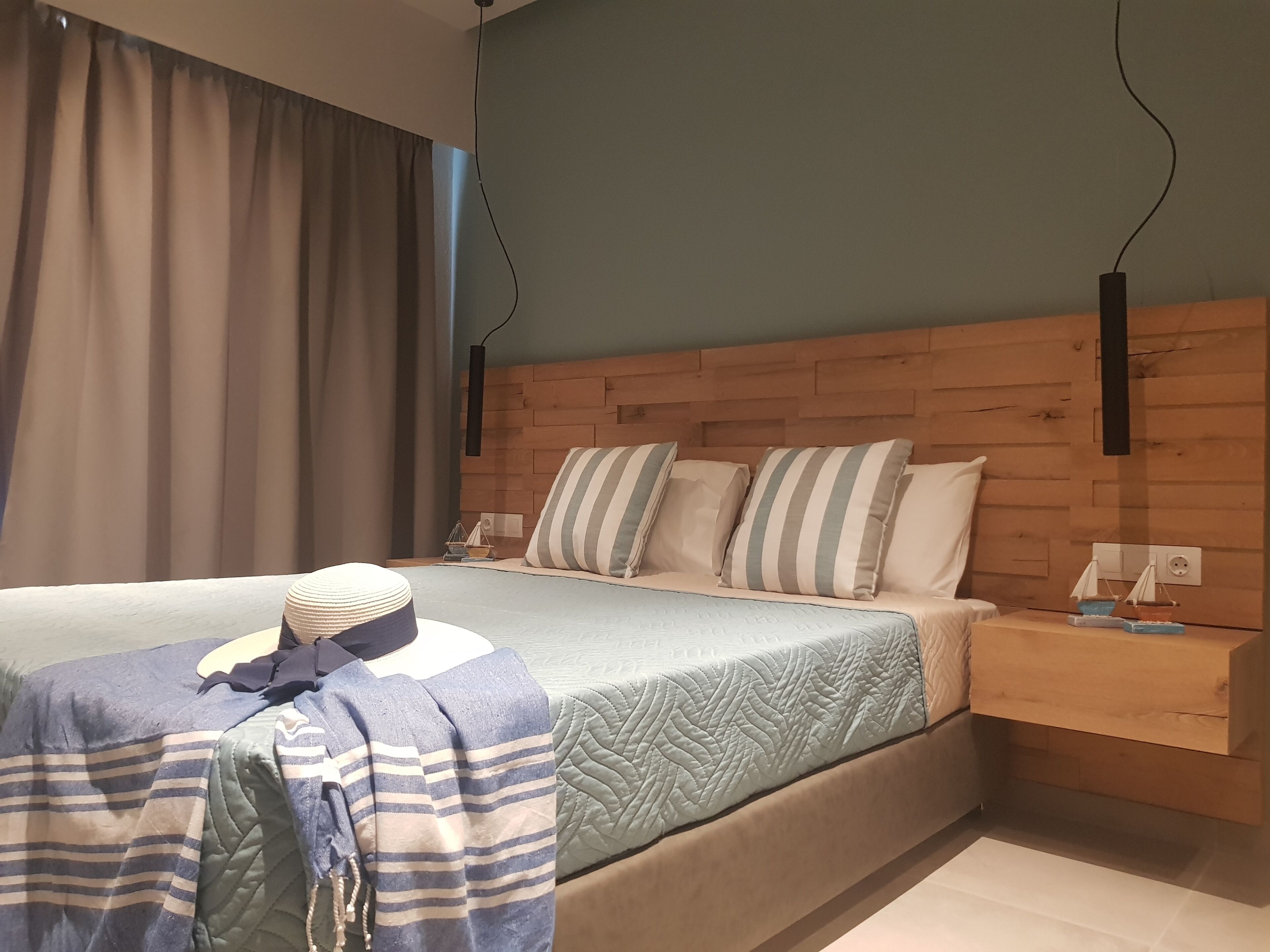 A neatly made bed with striped bedding, a bedside table with a lamp, and a wooden headboard.