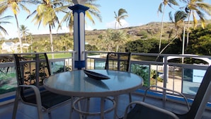 A round table with chairs on a balcony overlooking palm trees and a hilly landscape. - La Villa Allamanda (Rodrigues Island)