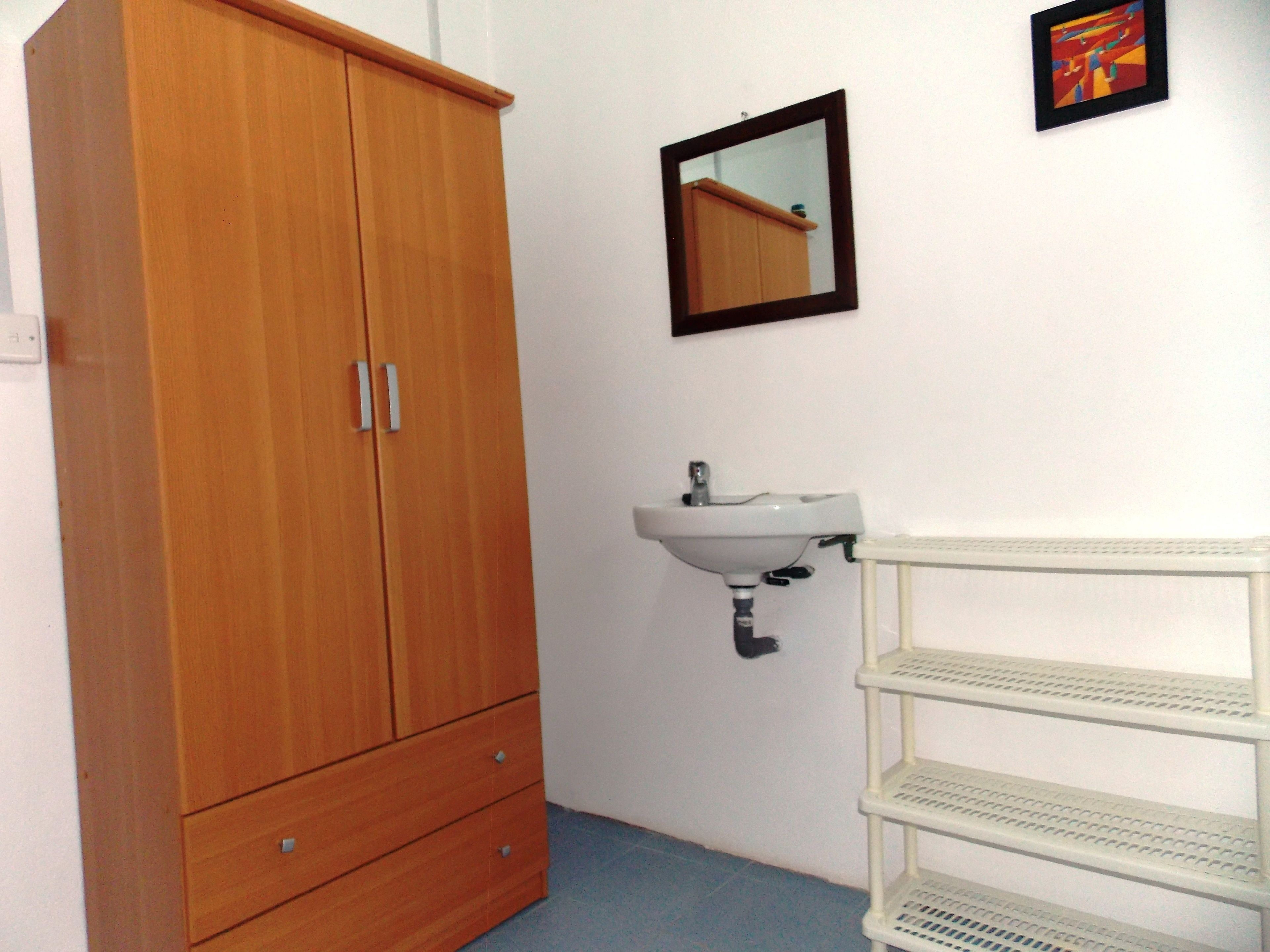 A bathroom with a wooden wardrobe, a white sink, and a mirror.