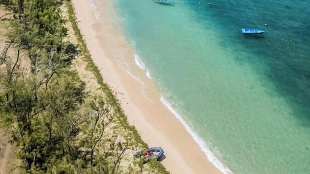 A coastal landscape with a beach, boats, and dense greenery. - La Villa Allamanda (Rodrigues Island)