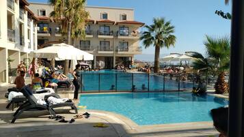 Alberca al aire libre, sombrillas en la alberca y camastros