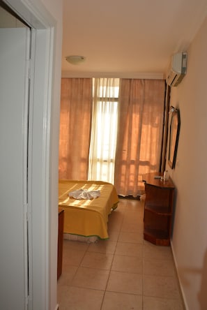 Ein Schlafzimmer mit Bett, Schminktisch, Spiegel und einem Fenster mit Vorhängen.