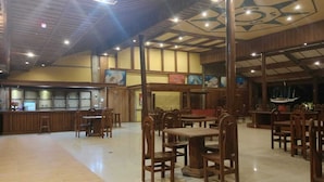 Un restaurant spacieux, doté de meubles en bois et d’un plafond haut.