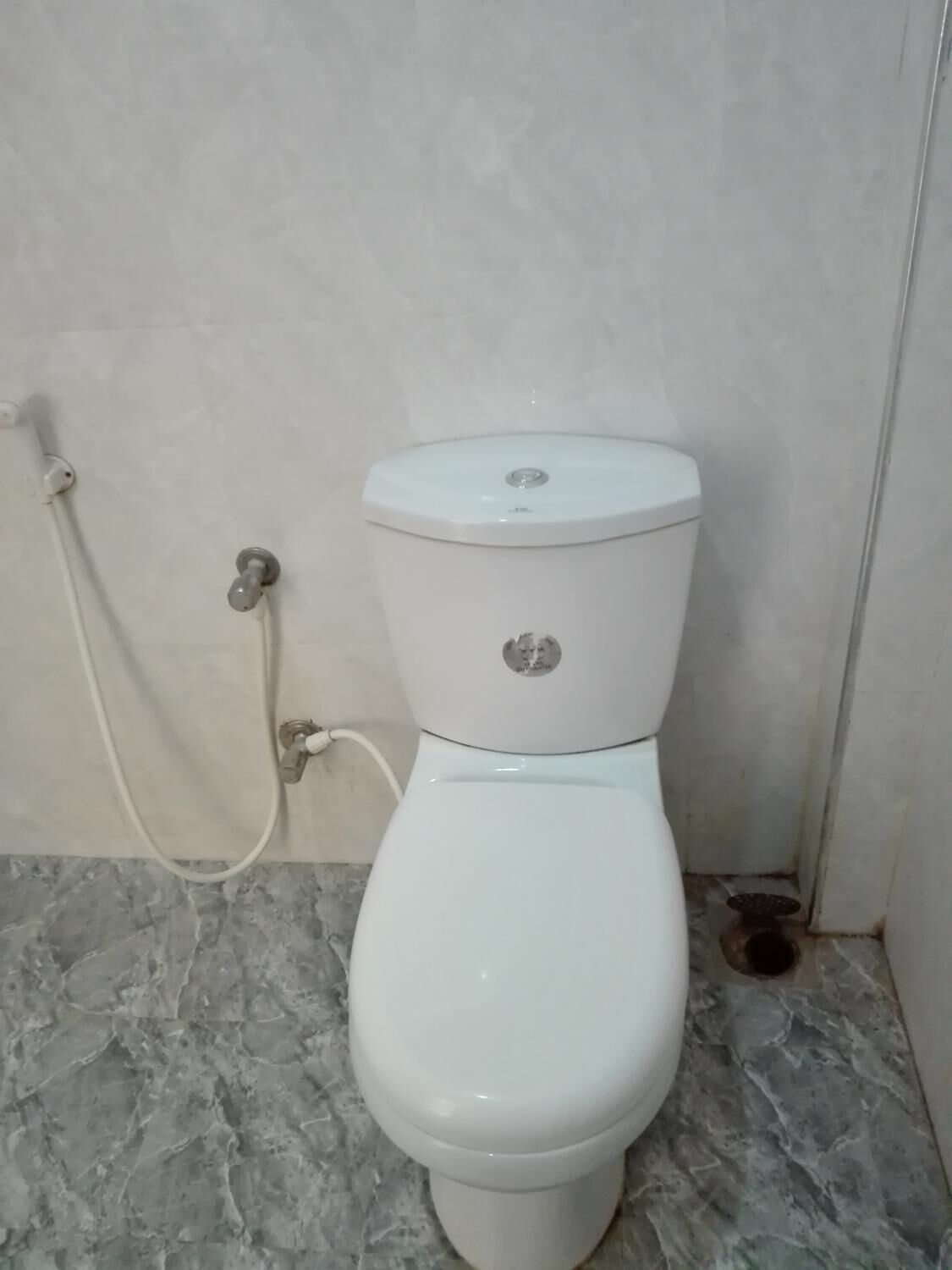 Un inodoro con asiento bidé en un baño con suelo de mármol.