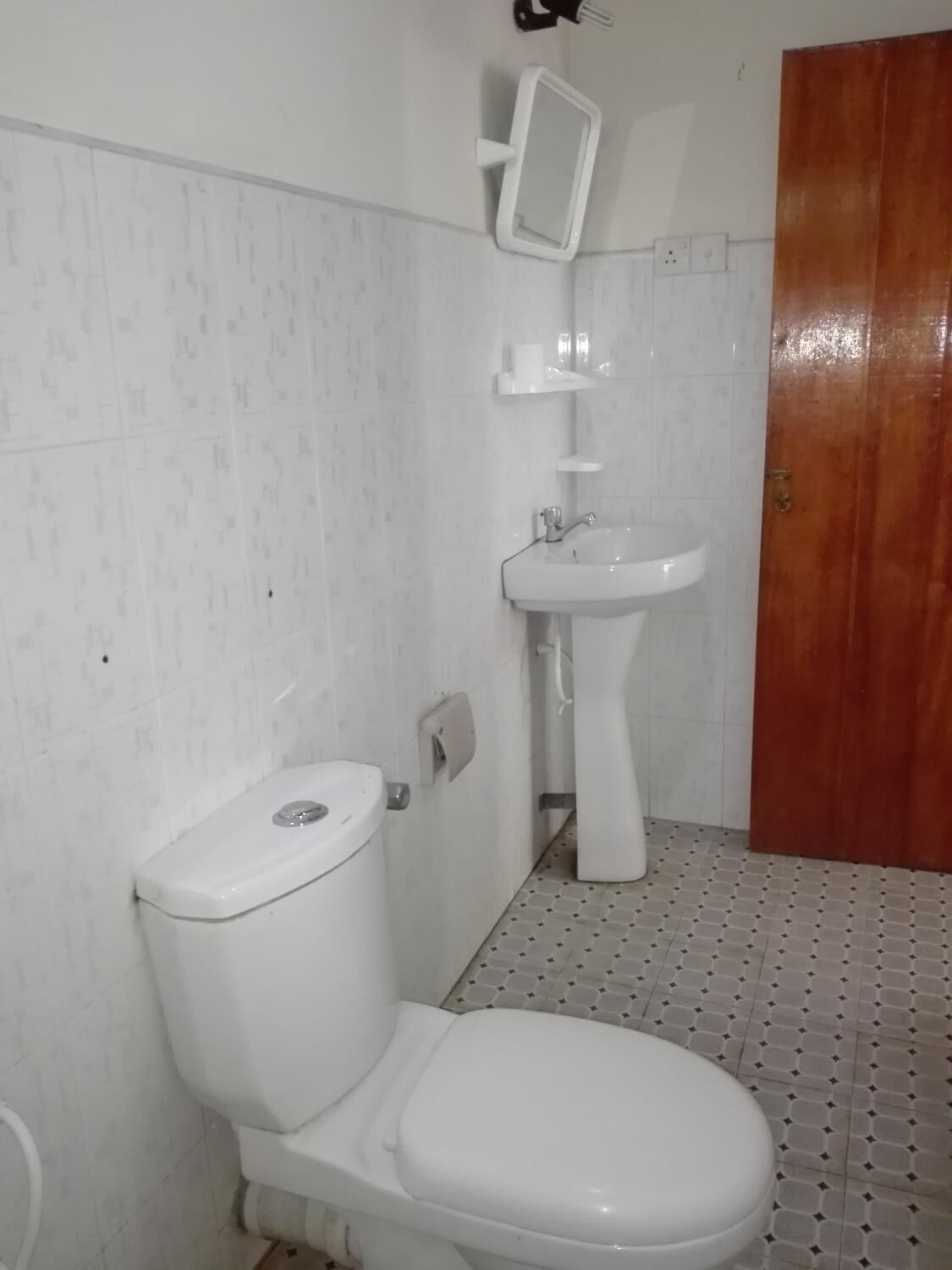 Une salle de bain avec des toilettes, un lavabo et un miroir.