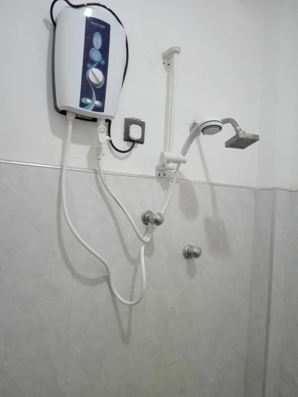 A wall-mounted shower unit with a control panel, a handheld showerhead, and a fixed showerhead.