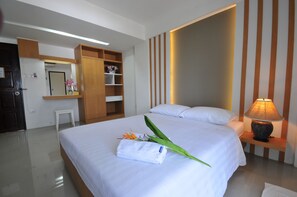 A neatly made bed with a folded towel and flowers, a bedside lamp, and a wooden wardrobe in a hotel room. - Beerapan Hotel (Bangkok)