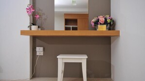 A small white stool under a wooden shelf with a potted orchid and a bouquet of flowers. - Beerapan Hotel (Bangkok)