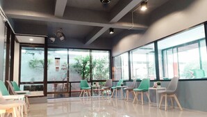 A modern indoor space with large windows, green chairs, and a polished floor. - Beerapan Hotel (Bangkok)