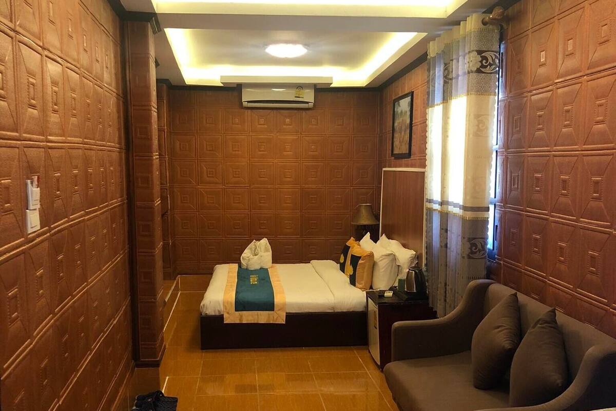 Een hotelkamer met een groot bed, een bank, een klein tafeltje en een spiegel.