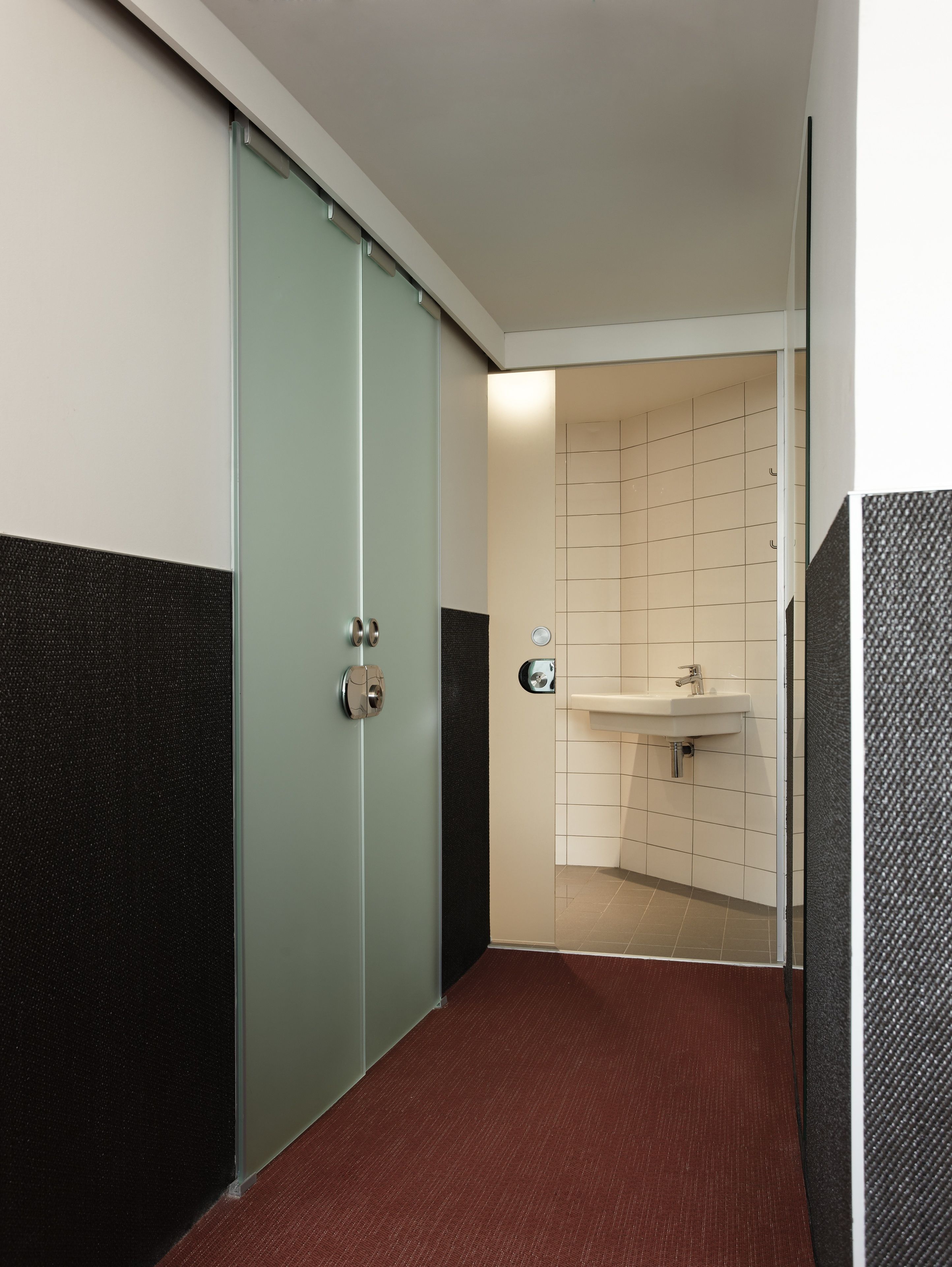 A modern bathroom with a glass door, a sink, and a tiled wall.