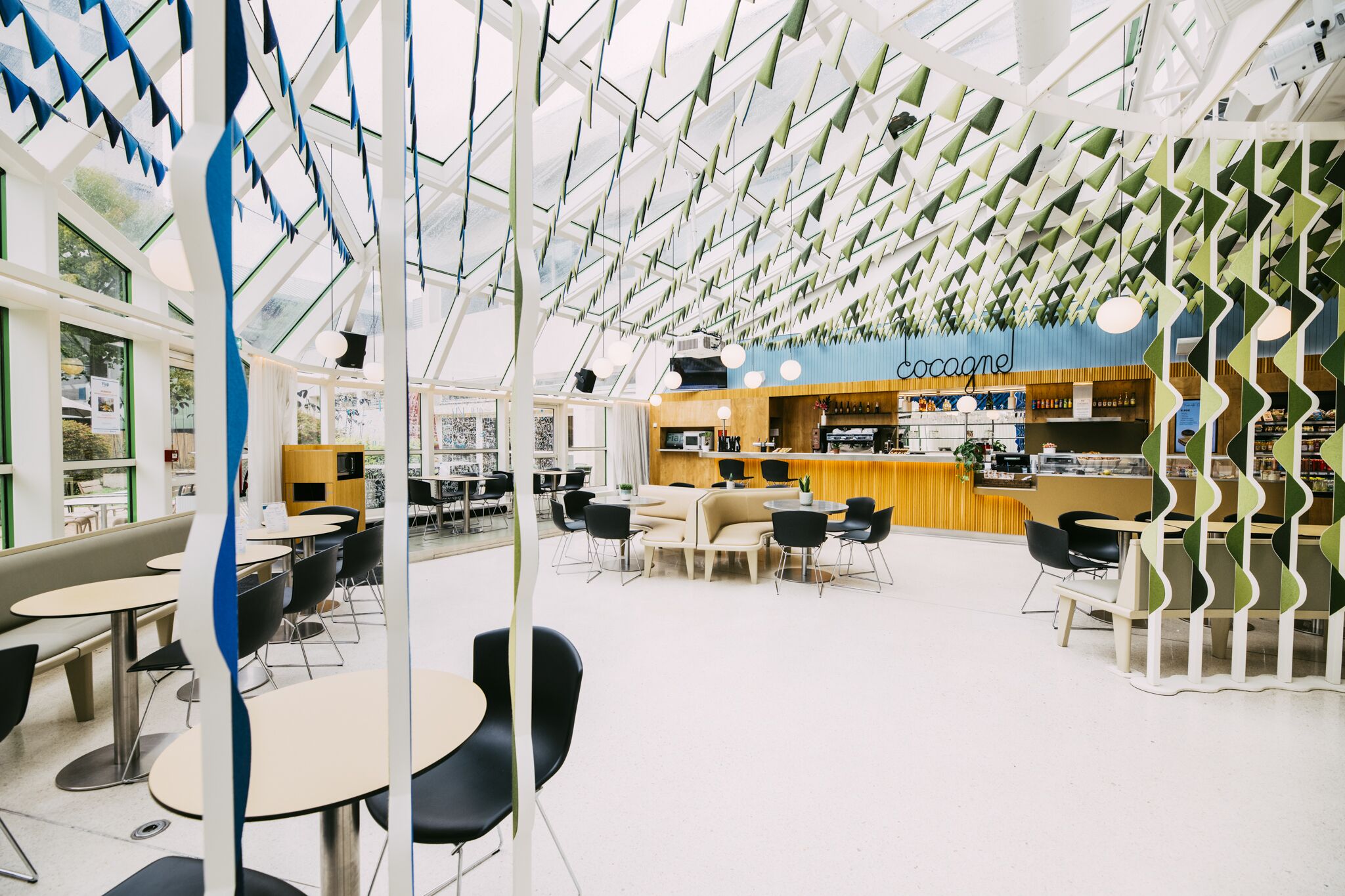 Een modern café met een centrale toonbank, zitgedeeltes en een opvallend plafondontwerp.