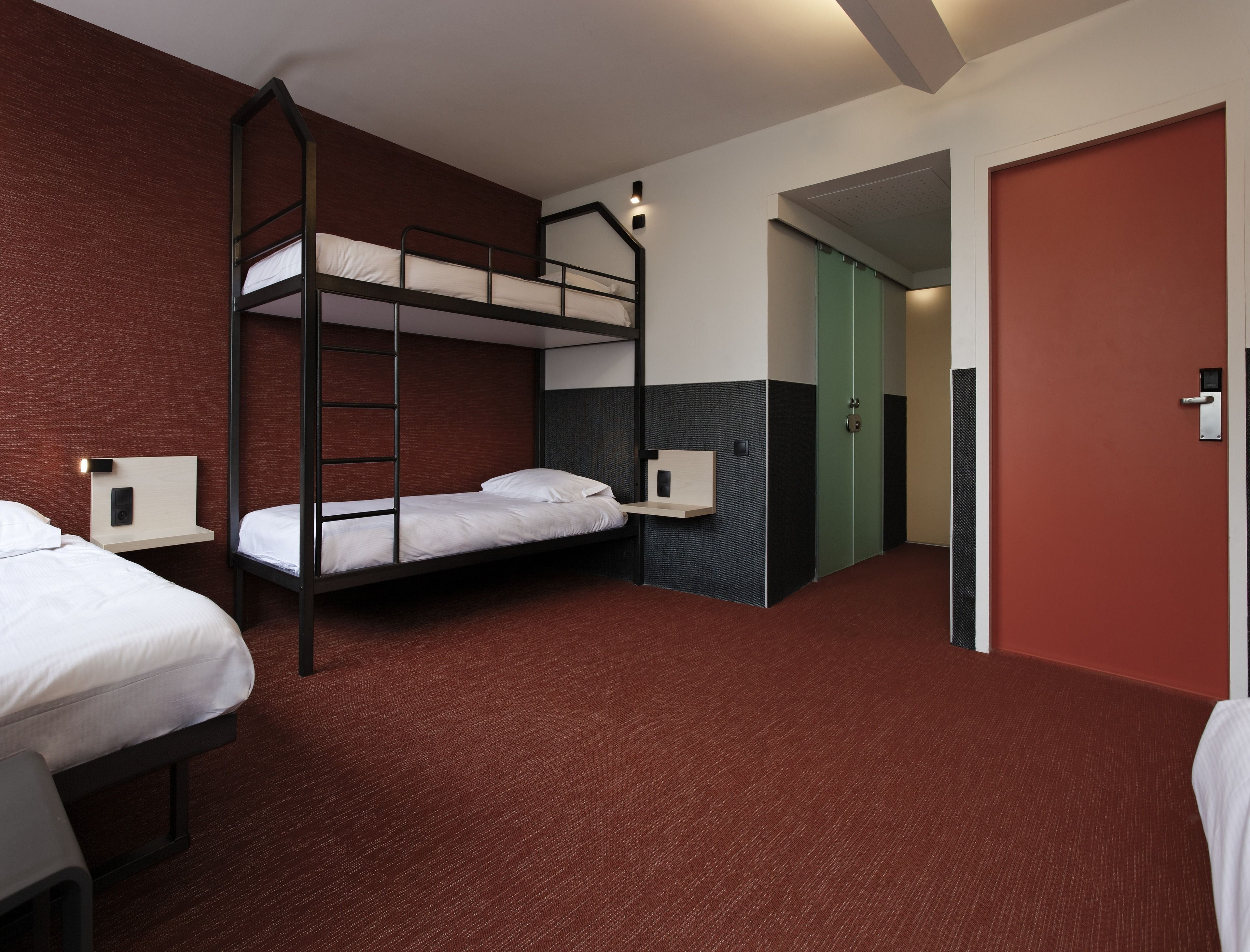 Une chambre d’hôtel avec des lits superposés, un bureau, une chaise, une armoire et une porte.