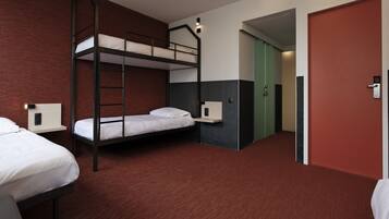 Une chambre d’hôtel avec des lits superposés, un bureau, une chaise, une armoire et une porte.