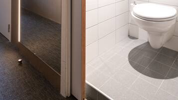 Une salle de bain moderne équipée de toilettes, d’une douche et d’un miroir.