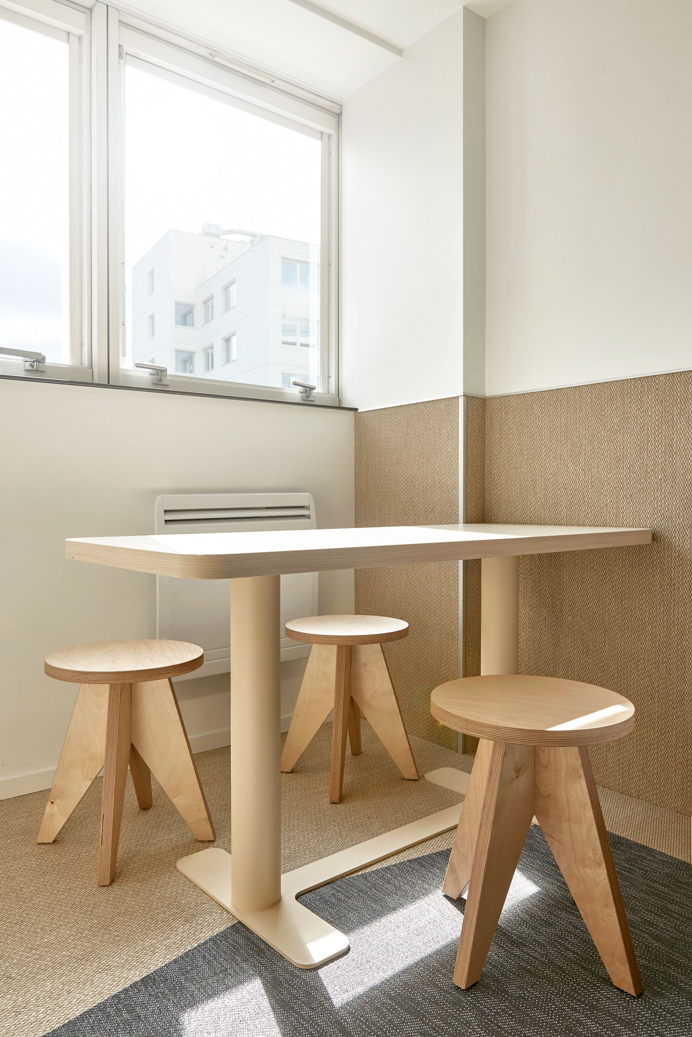 Een hoekzaal met een groot raam, een witte radiator en een beige muur met textuur.