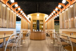 A restaurant interior with a central counter, wooden chairs, and a menu board. - FIAP - Hostel (Paris)
