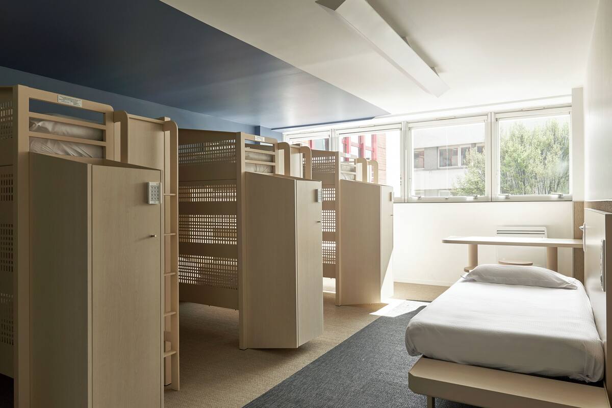 A room with bunk beds, a desk, and a window with a view of trees.