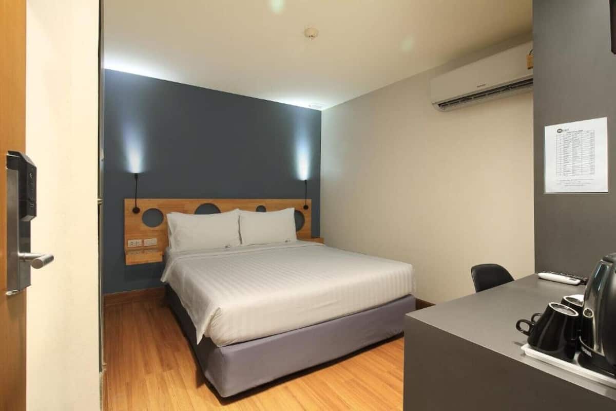 A compact hotel room with a bed, a desk, and a coffee machine.