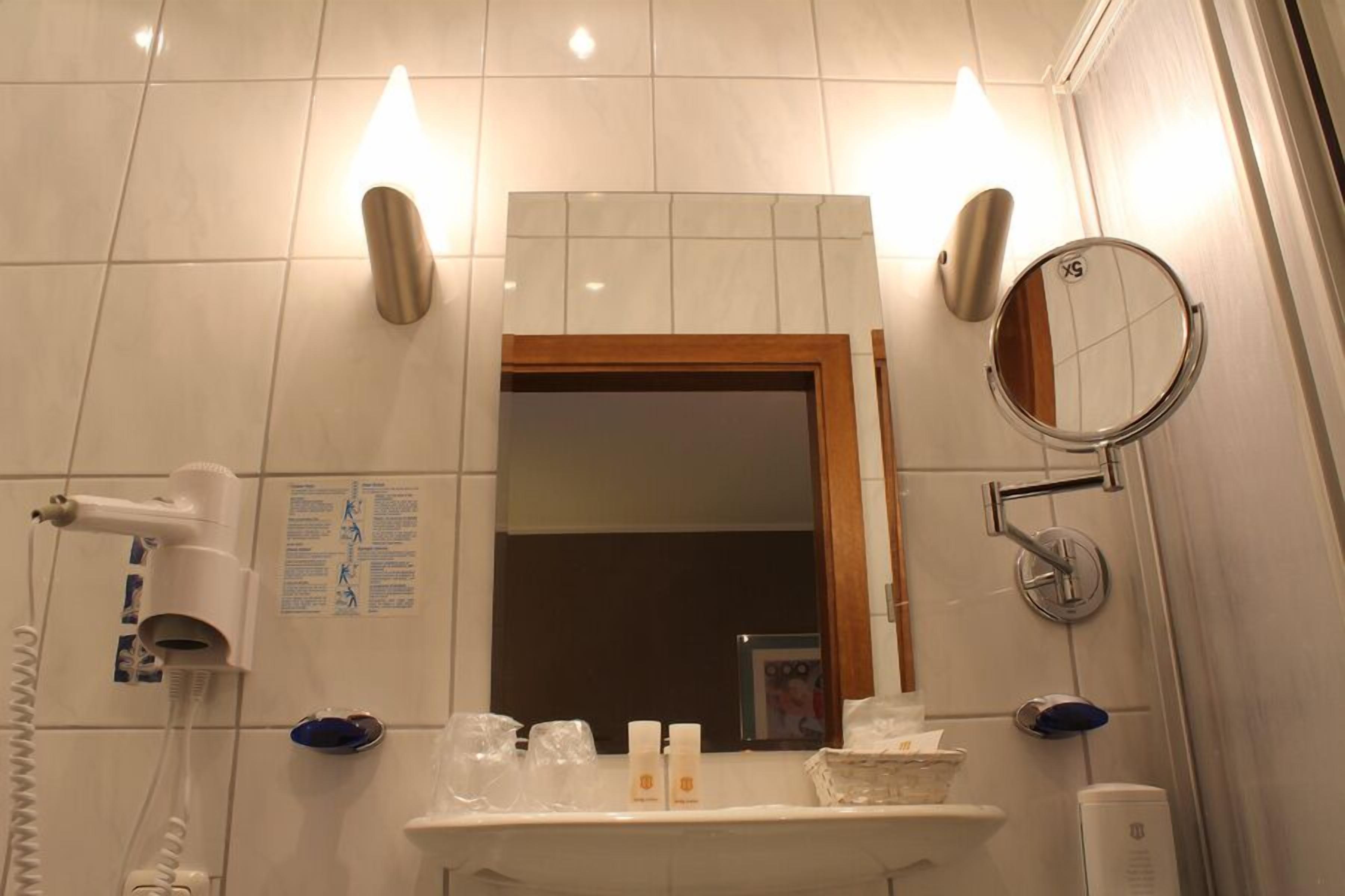 A bathroom with a mirror, a hairdryer, and toiletries on the counter.