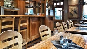 Un restaurante con barra de madera y zona de comedor, que incluye taburetes y mesas.
