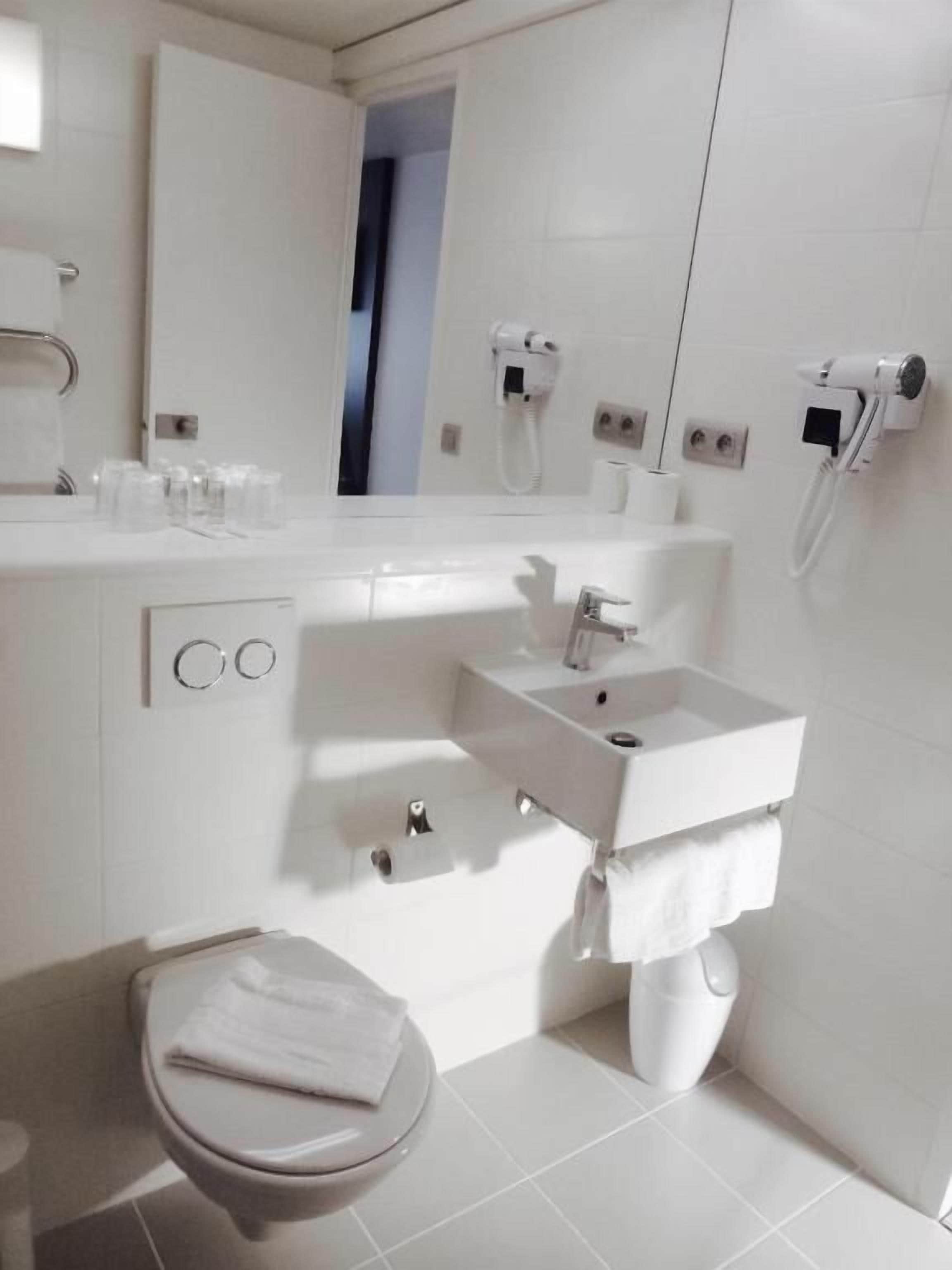 A modern bathroom with a toilet, sink, and mirror.
