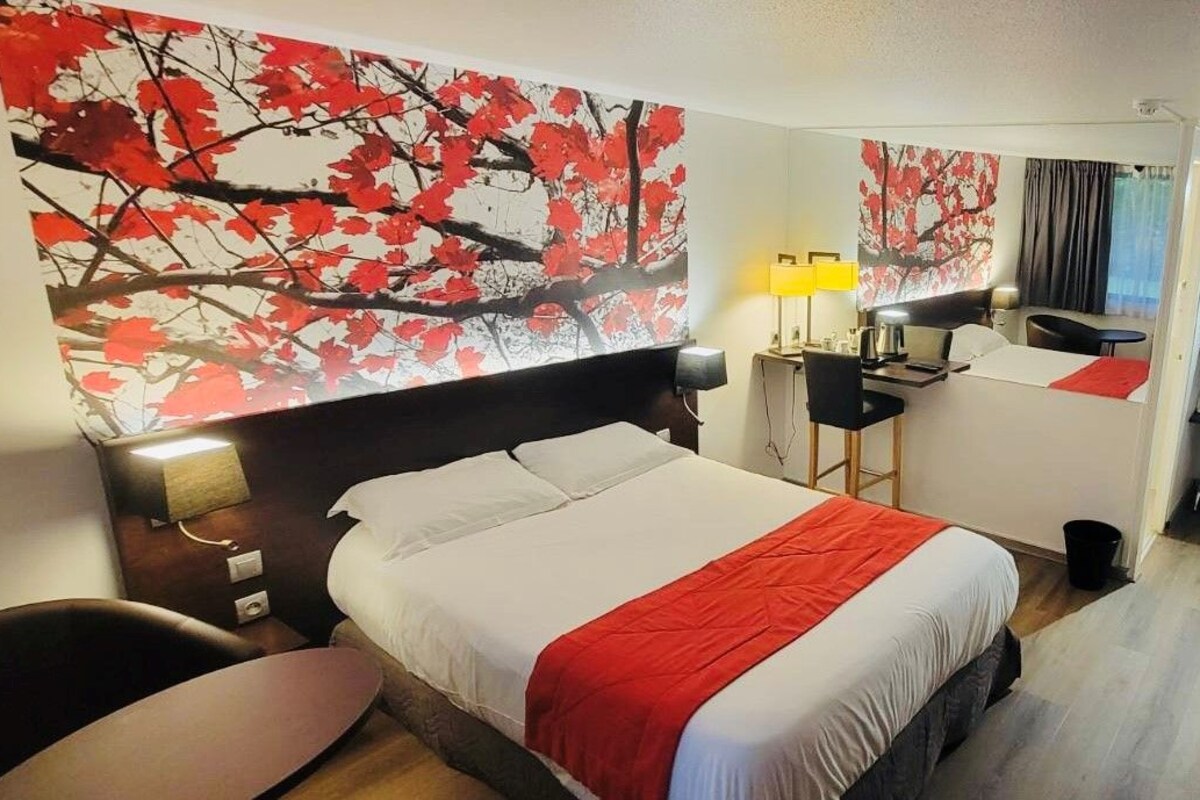 A hotel room with a bed, a desk, a chair, and a TV.