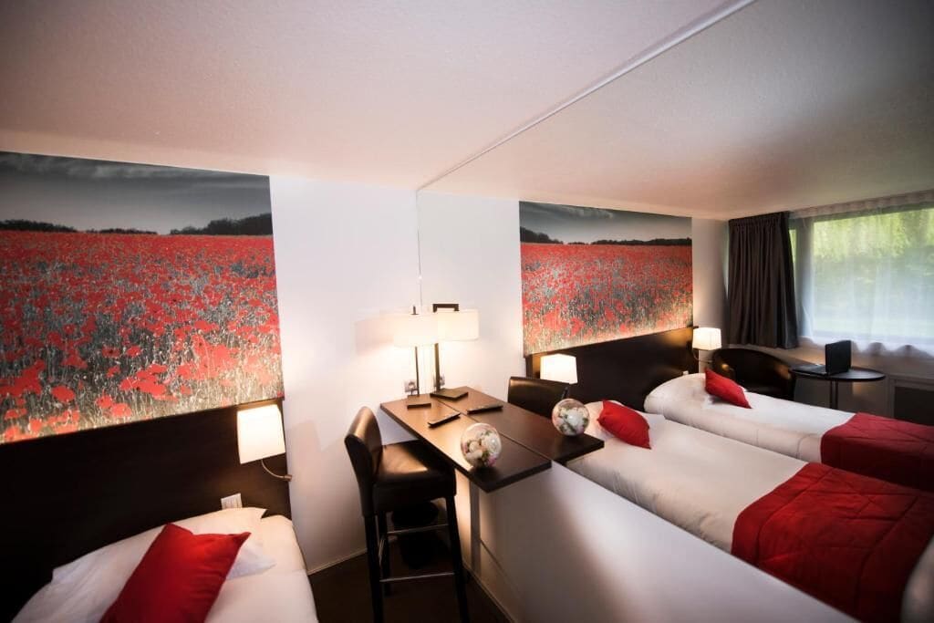 Habitació d'hotel amb dos llits, un escriptori i una cadira.