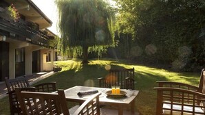 A patio with wooden furniture, a table, and chairs. - Hôtel Pavillon des Gâtines (Plaisir)