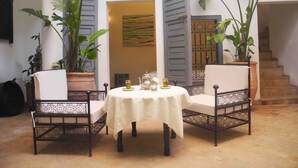 A cozy patio with a round table, two chairs, and potted plants. - Riad Linda (Marrakech)