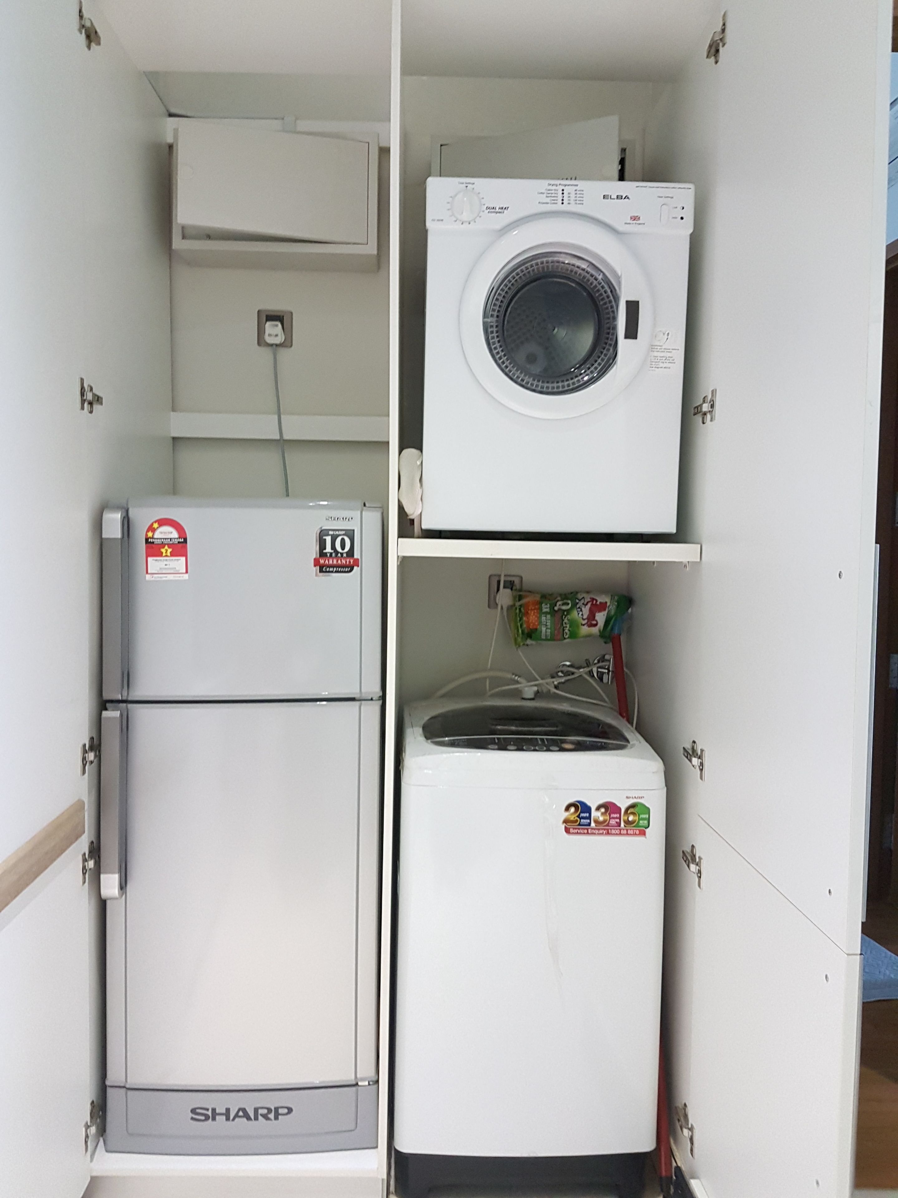 Un cuarto de servicio compacto con un refrigerador Sharp, una lavadora Elba y un congelador pequeño.