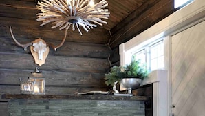 A rustic interior with a stone fireplace, a chandelier, and a wooden ceiling. - Norefjellhytta  (Krodsherad)