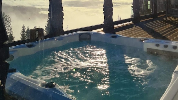 A hot tub with a wooden deck and a view of a body of water and mountains. - Norefjellhytta  (Krodsherad)