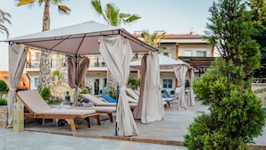 A covered outdoor lounge area with sun loungers and a pergola structure. - Greek Pride Ηotel and Apartments (Kassandra)