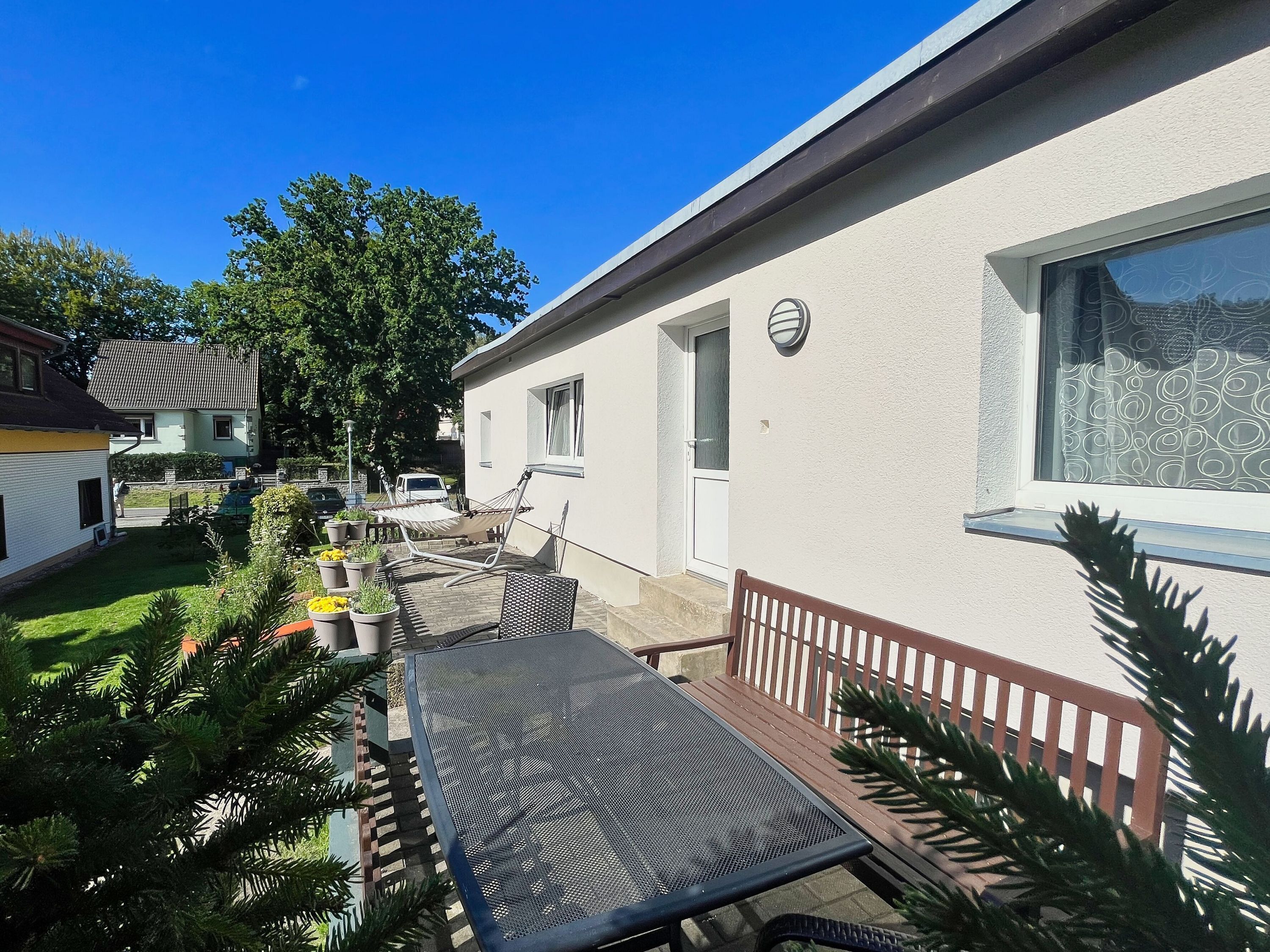 A residential building with a patio area, a hammock, a table, and a bench.