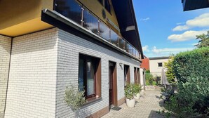 A two-story building with a balcony, brick facade, and potted plants. - Ferienhus Baabe (Ostseebad Baabe)
