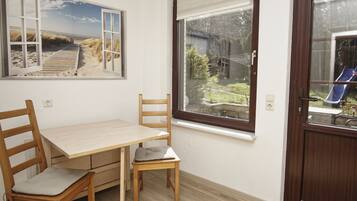 A room with a wooden table and chairs, a window with a view of a garden and a slide, and a door with a window.