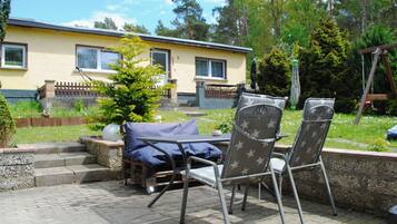 A patio with two chairs, a table, and a small tree.