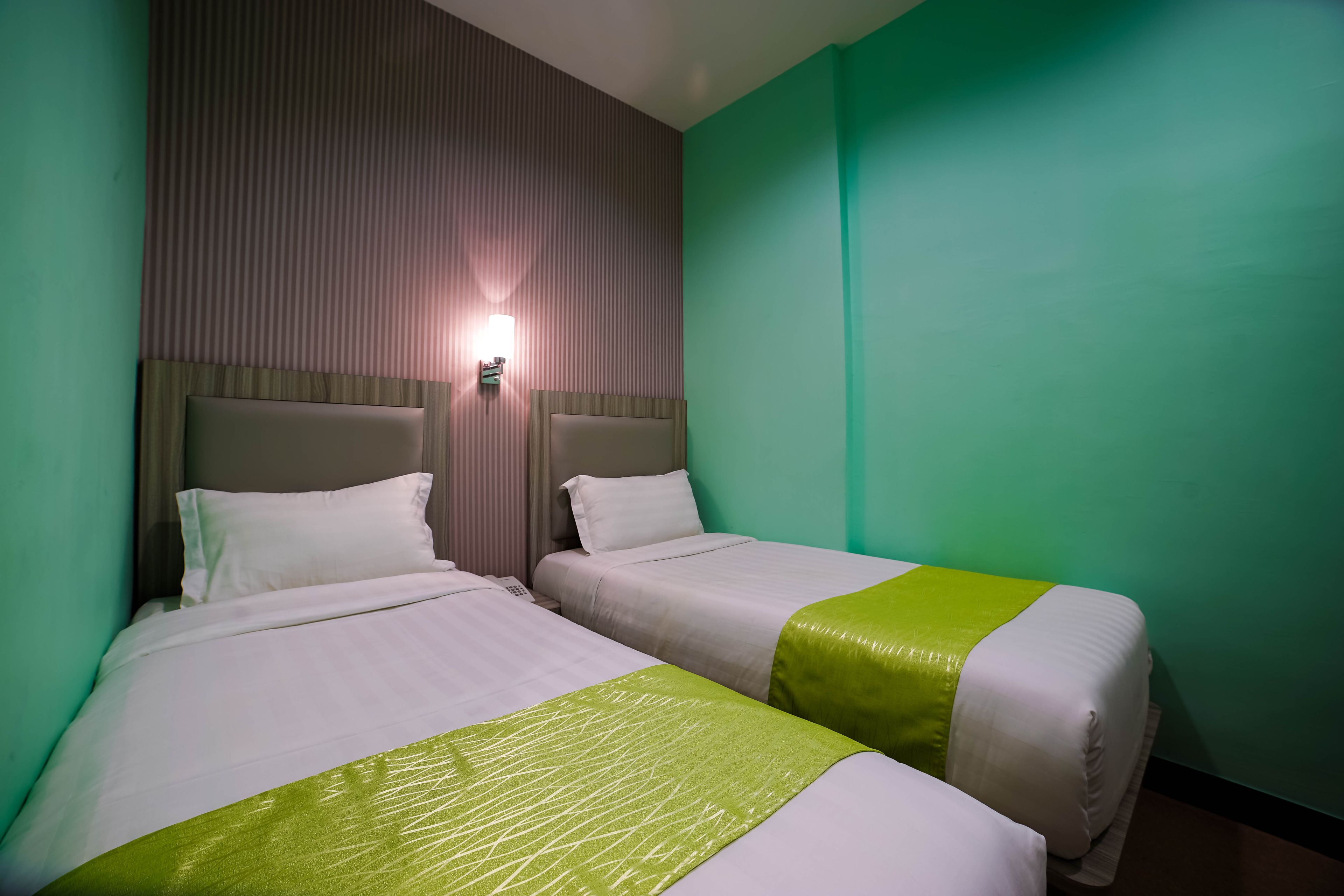 A hotel room with two beds, each with a headboard and a bedside table.