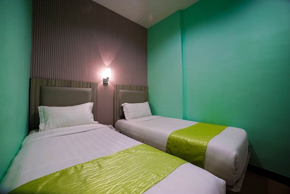 A hotel room with two beds, each with a headboard and a bedside table.