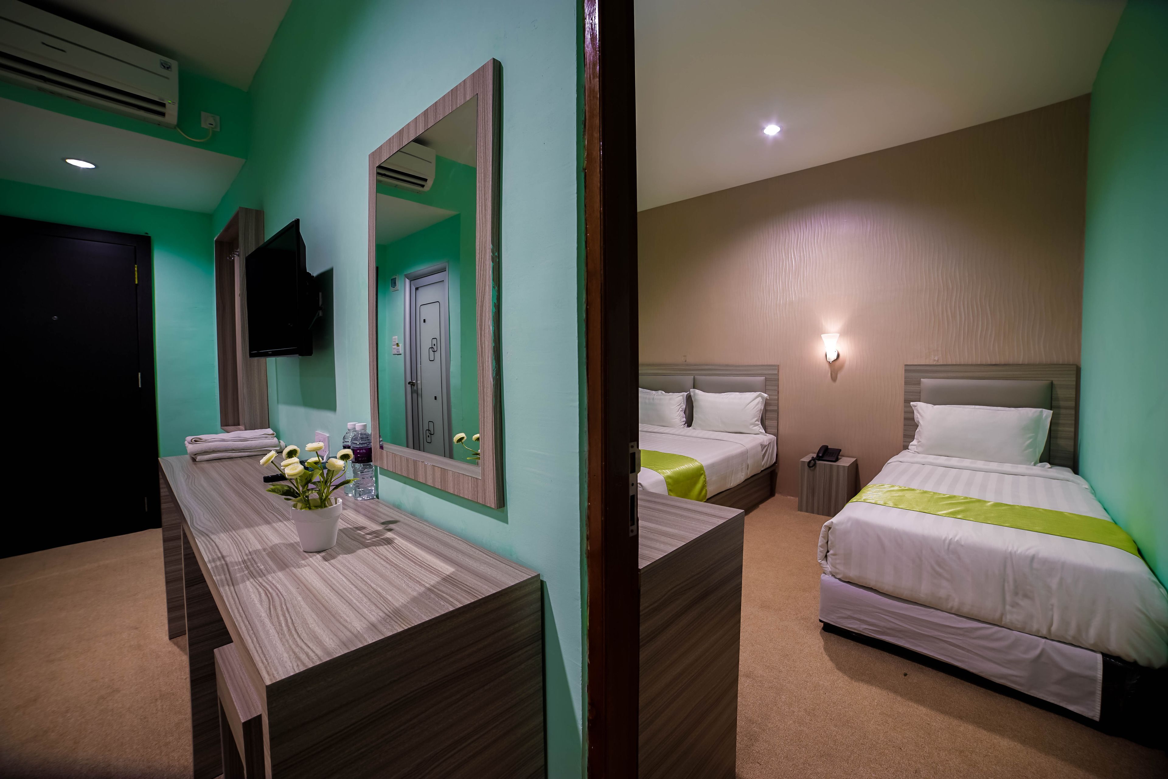 A hotel room with a bed, bedside table, and a mirror.