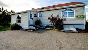 Un bâtiment d’un seul étage doté d’une porte de garage, d’un petit porche et d’une fenêtre sur laquelle est affiché un panneau indiquant « BUREAU ».