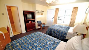 Une chambre d’hôtel avec deux lits, une télévision, une chaise et une porte donnant sur un balcon.