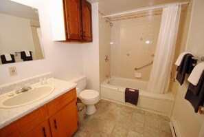 A bathroom with a sink, toilet, bathtub, and a shower curtain. - Keppoch Inns (Post Road)