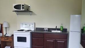 Une cuisine équipée d’une cuisinière, d’un four à micro-ondes et d’un réfrigérateur. On y trouve un meuble en bois et un plan de travail.