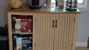 A kitchenette with a coffee maker, a basket of snacks, and a coffee machine.